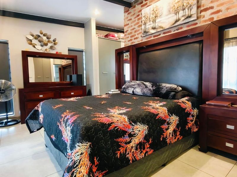 Spacious bedroom featuring an exposed brick accent wall, built-in cabinetry, tiled flooring, and an integrated air conditioning unit.