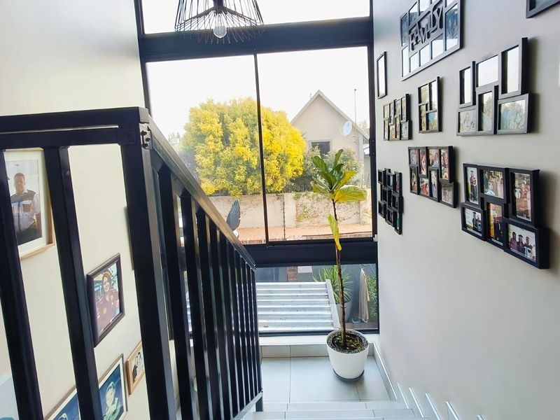 A bright staircase landing featuring a large window, tiled flooring, and a modern metal balustrade, providing natural light and access to the upper level.