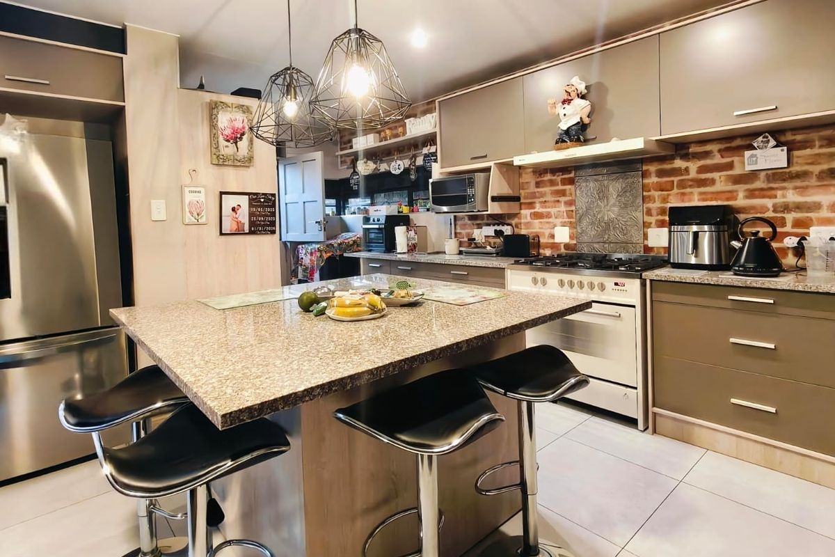 A well-appointed kitchen featuring a central granite island, exposed brick backsplash, and modern cabinetry, creating a warm and functional culinary space.