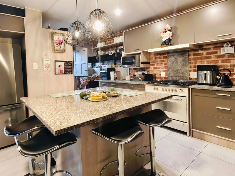A well-appointed kitchen featuring a central granite island, exposed brick backsplash, and modern cabinetry, creating a warm and functional culinary space.