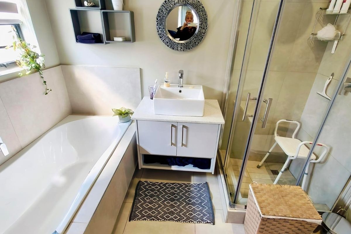 A well-maintained bathroom featuring a built-in bathtub, a modern vanity with a vessel sink, and a separate glass-enclosed shower.