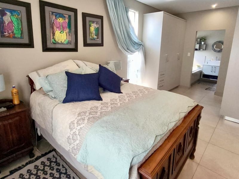 A well-maintained bedroom featuring tiled flooring, built-in wardrobe storage, and an open-plan layout leading into an en-suite bathroom area.