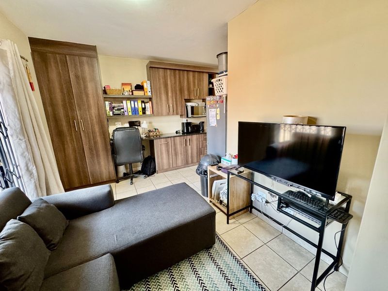 Open-plan living area featuring tiled flooring and integrated cabinetry with a built-in microwave and workspace area.