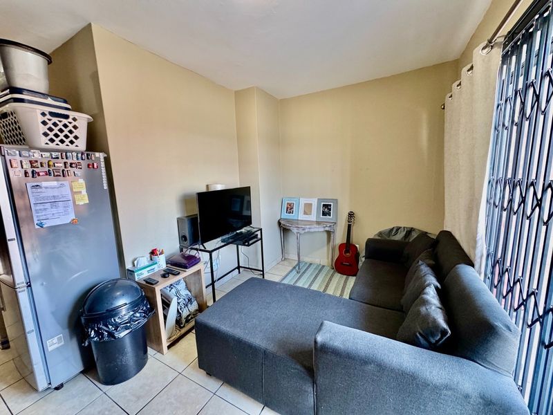 An open-plan living area featuring tiled flooring and a security gate, providing a functional space for daily living.