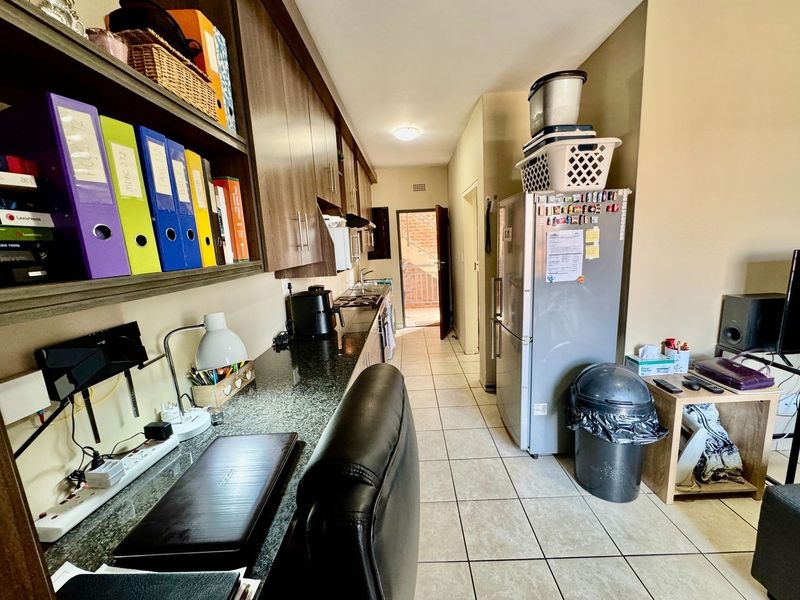 A functional kitchen featuring granite countertops, built-in cabinetry, and tiled flooring, leading to an exterior doorway.