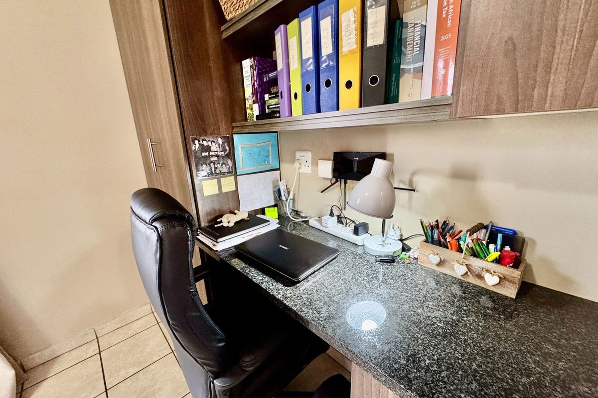 A functional home office space featuring a built-in desk with granite countertop and integrated overhead shelving units.