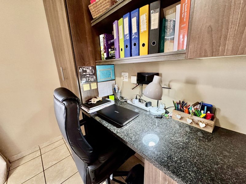 A functional home office space featuring a built-in desk with granite countertop and integrated overhead shelving units.
