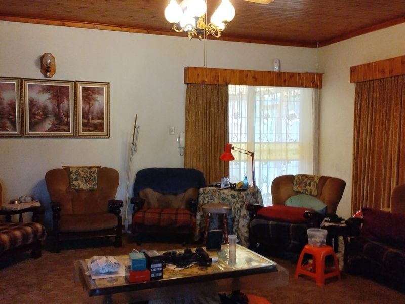 A traditional living room featuring a timber-paneled ceiling, wall-mounted air conditioning, and timber pelmets over the window treatments.
