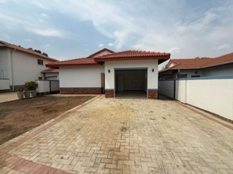 Front view of the property featuring a paved driveway, a single garage, and a well-maintained boundary wall with a tiled roof finish.