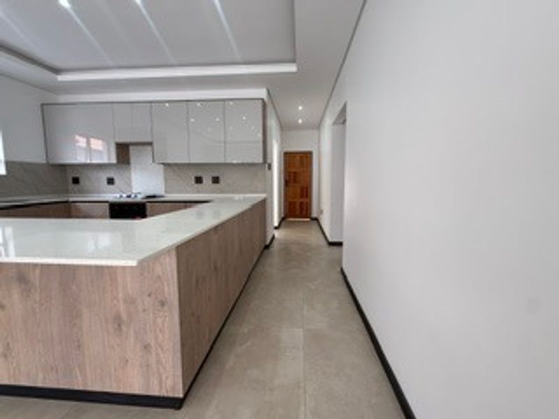 Modern kitchen featuring sleek cabinetry, stone countertops, integrated hob, and recessed lighting, offering a clean and contemporary culinary space.