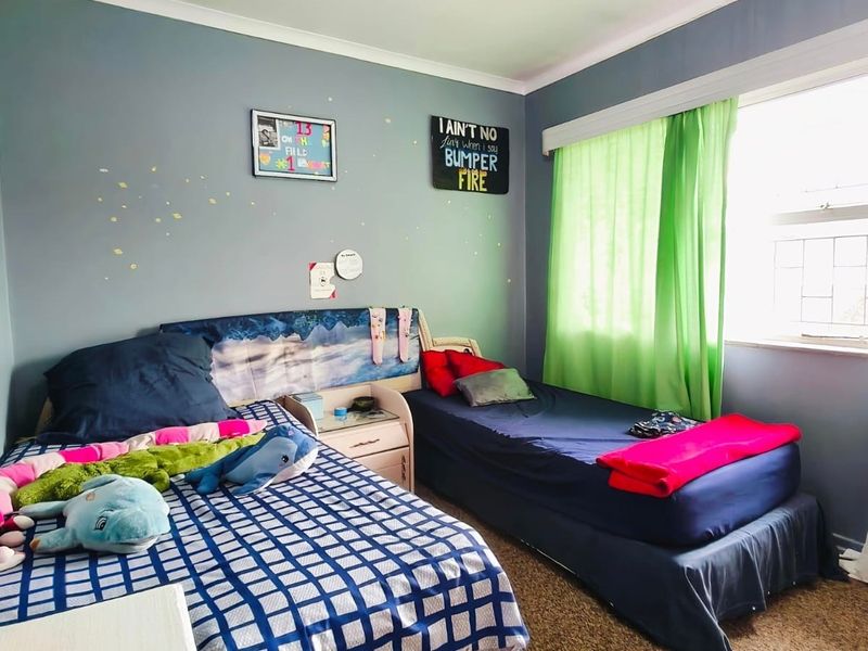 A functional bedroom featuring neutral wall paint, coving, and a large window allowing for natural light.