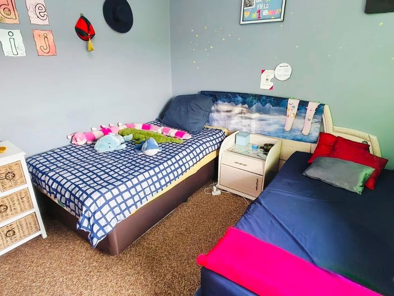 A bedroom featuring carpeted flooring and neutral wall paint, currently configured with two beds.