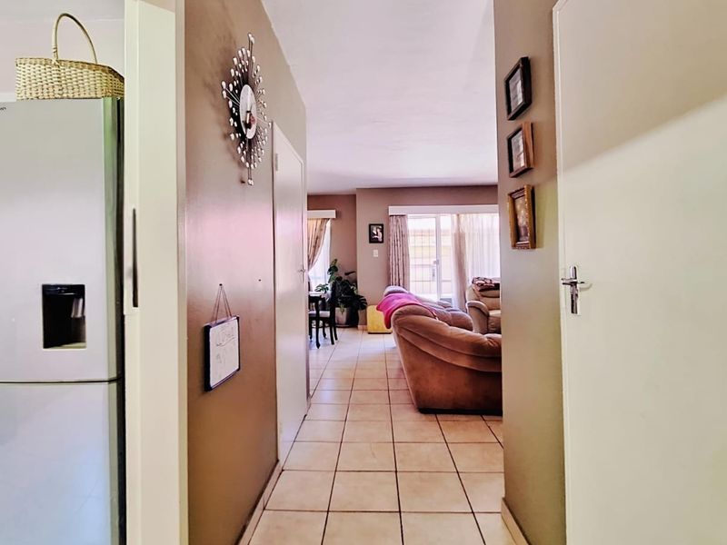 A view through a central hallway connecting the kitchen area to the open-plan living space, featuring tiled flooring throughout.