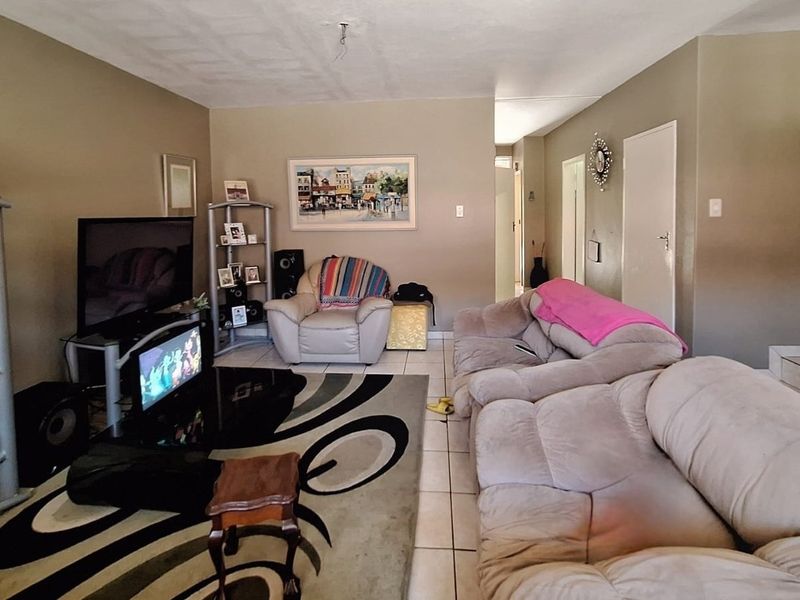 A spacious living room featuring tiled flooring and an integrated staircase, providing a functional layout for comfortable family living.