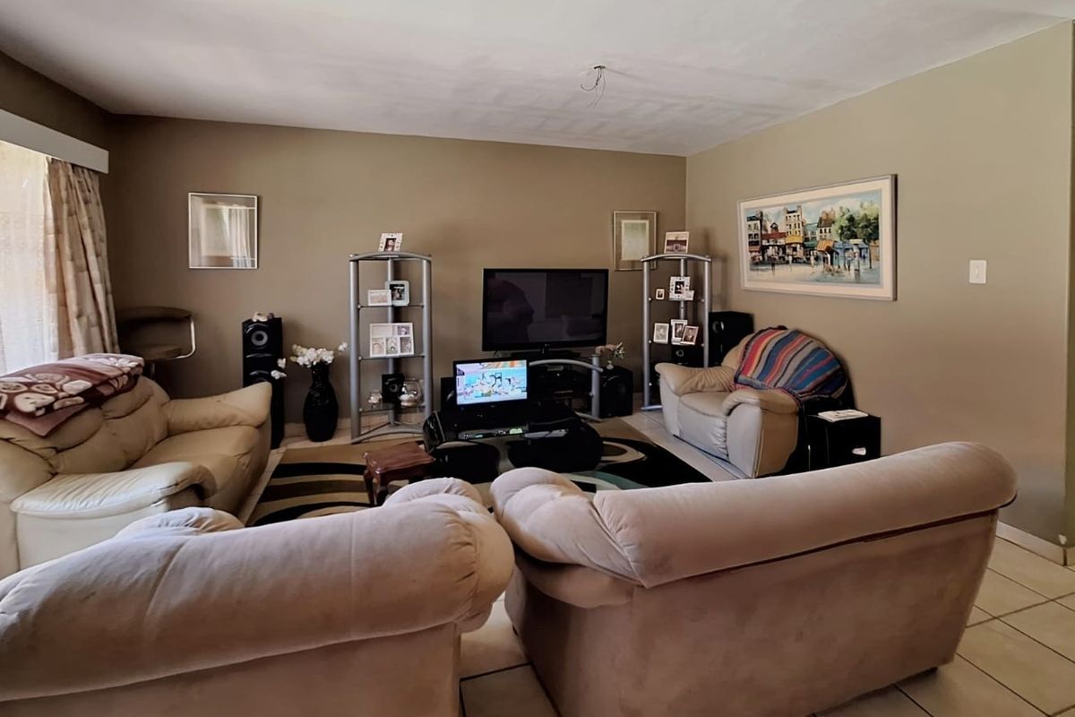 A spacious living room featuring neutral wall tones and tiled flooring, with an exposed ceiling wiring point requiring a light fixture installation.