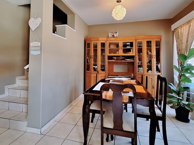 A dining area featuring tiled flooring, a staircase, and built-in wooden display cabinetry, offering a functional space for meals.