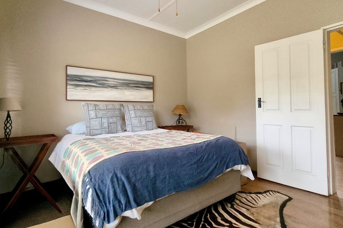 A well-proportioned bedroom featuring neutral wall tones, classic cove cornicing, and a traditional panelled door leading to an adjacent space.