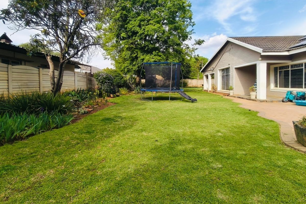 A spacious rear garden featuring a well-maintained lawn, paved patio area, and secure boundary walling, providing a private outdoor space.