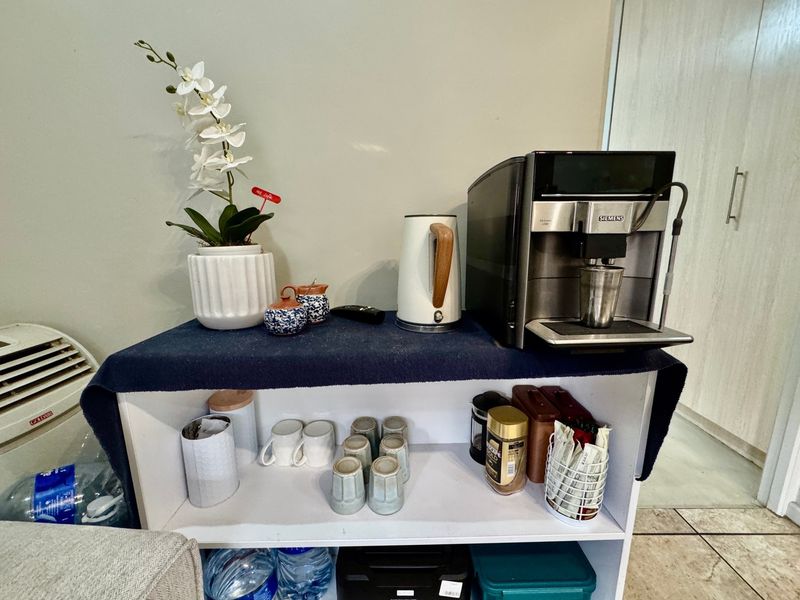 A close-up view of a small shelving unit used as a coffee station with various kitchen accessories and appliances.