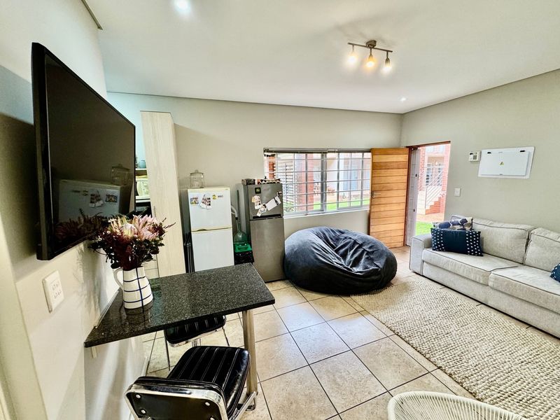 Open-plan living area featuring tiled flooring, a granite breakfast counter, and direct access to the exterior through a timber door.