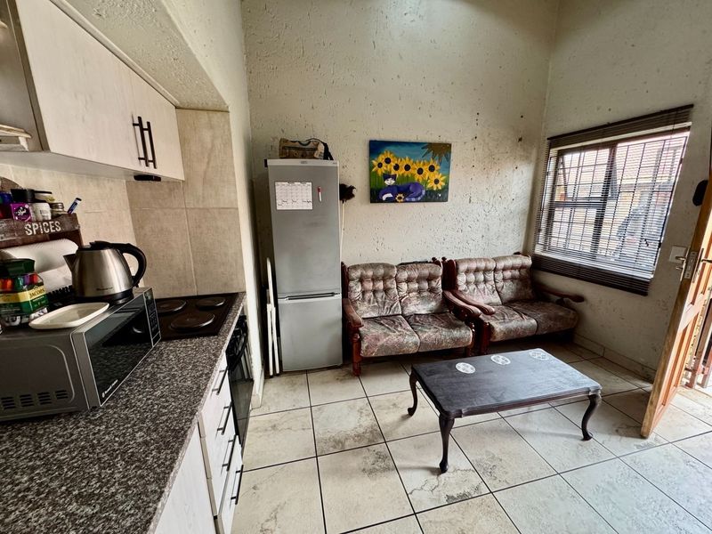 Compact open-plan kitchen and living area featuring tiled flooring, built-in cabinetry with granite countertops, and an electric hob.