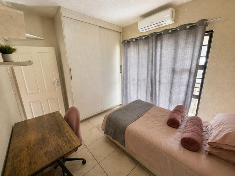 A compact bedroom featuring tiled flooring, a built-in wardrobe, and a wall-mounted air conditioning unit.