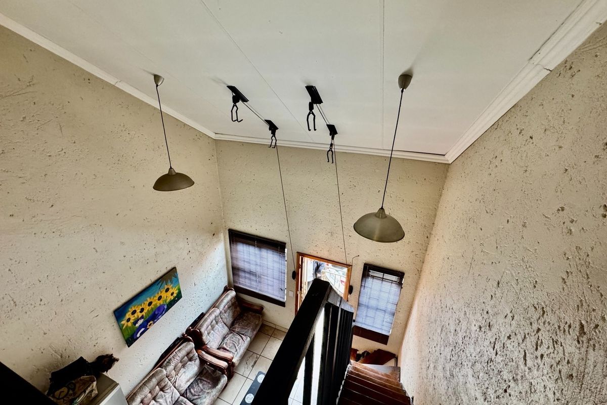 High-ceiling living area featuring a staircase, pendant lighting, and textured walls, viewed from an elevated perspective.