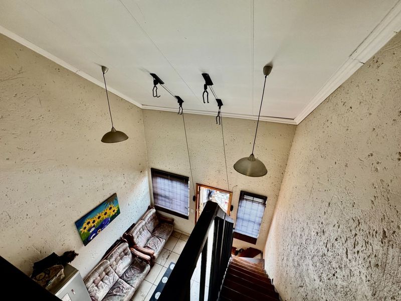 High-ceiling living area featuring a staircase, pendant lighting, and textured walls, viewed from an elevated perspective.