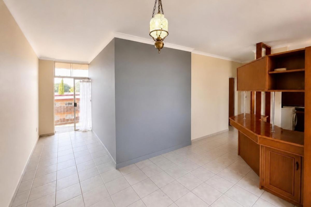 Open plan living area featuring tiled flooring, a built-in wooden breakfast bar, and direct access to a balcony through a sliding glass door.