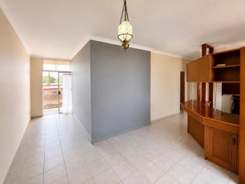 Open plan living area featuring tiled flooring, a built-in wooden breakfast bar, and direct access to a balcony through a sliding glass door.
