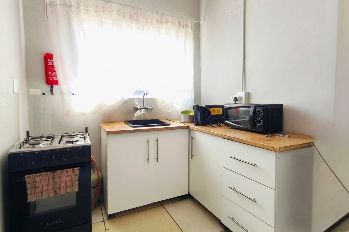 Compact kitchen featuring white cabinetry, wooden countertops, a sink, and a freestanding gas stove.