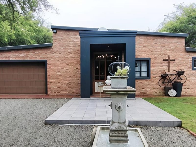 Front elevation of a modern brick house featuring a prominent dark-framed entrance, integrated garage, and a paved porch area.