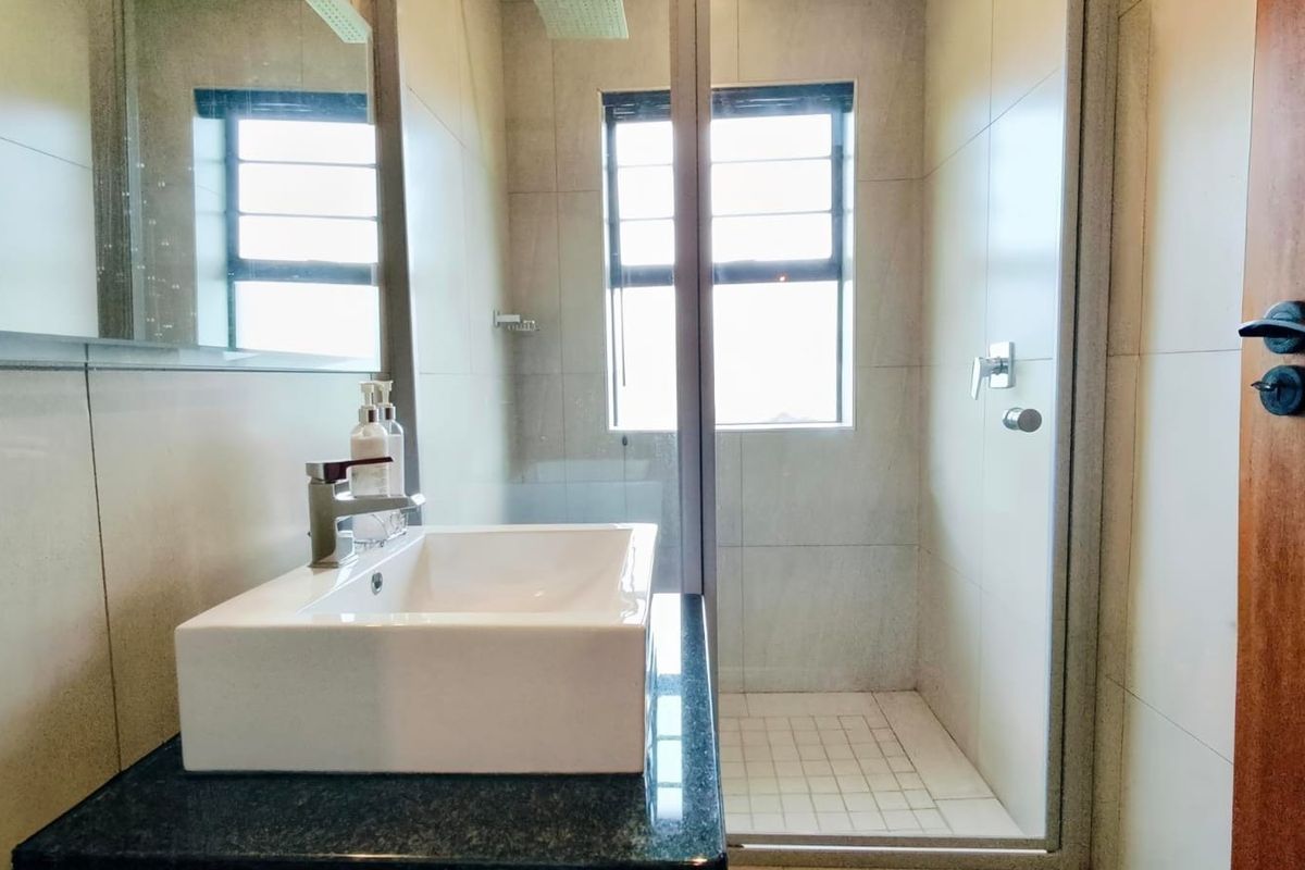 Modern bathroom featuring a vessel sink on a granite vanity countertop and a glass-enclosed shower with tiled finishes.