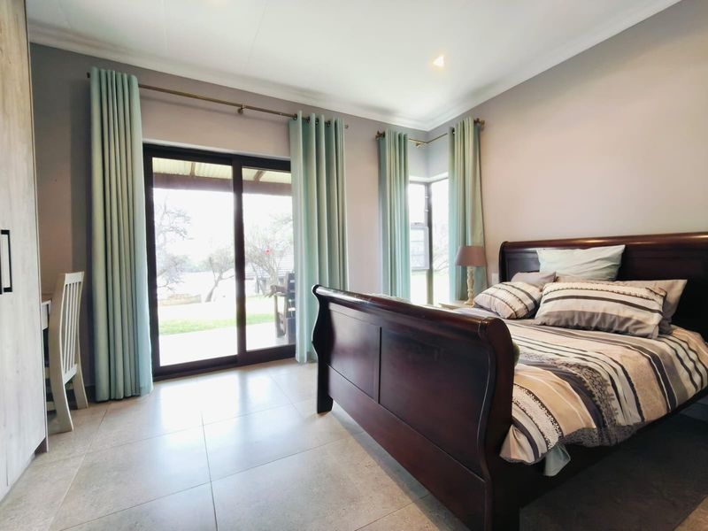 A well-lit bedroom featuring large sliding glass doors that provide direct access to the outdoor patio area and tiled flooring throughout.