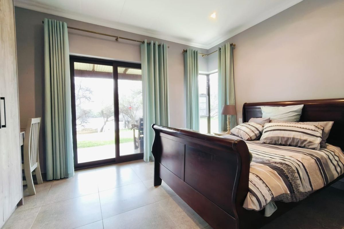 A well-lit bedroom featuring large sliding glass doors that provide direct access to the outdoor patio area and tiled flooring throughout.