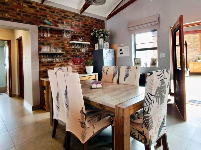 Dining area featuring an exposed brick feature wall, vaulted ceiling, and tiled flooring, with direct access to an outdoor patio space.