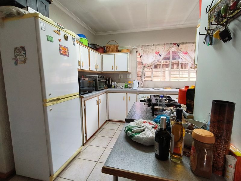 A functional kitchen featuring laminate countertops, built-in cabinetry, and ceramic floor tiles, offering a practical layout with a gas hob and sink area.