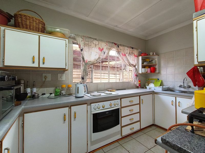 A functional kitchen featuring white cabinetry, laminate countertops, a built-in oven, and a tiled backsplash, offering a practical layout for daily meal preparation.