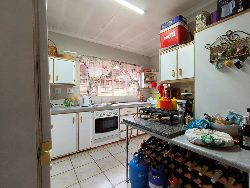 A functional kitchen featuring built-in cabinetry, tiled flooring, and a built-in oven, offering a practical layout with potential for modern updates.