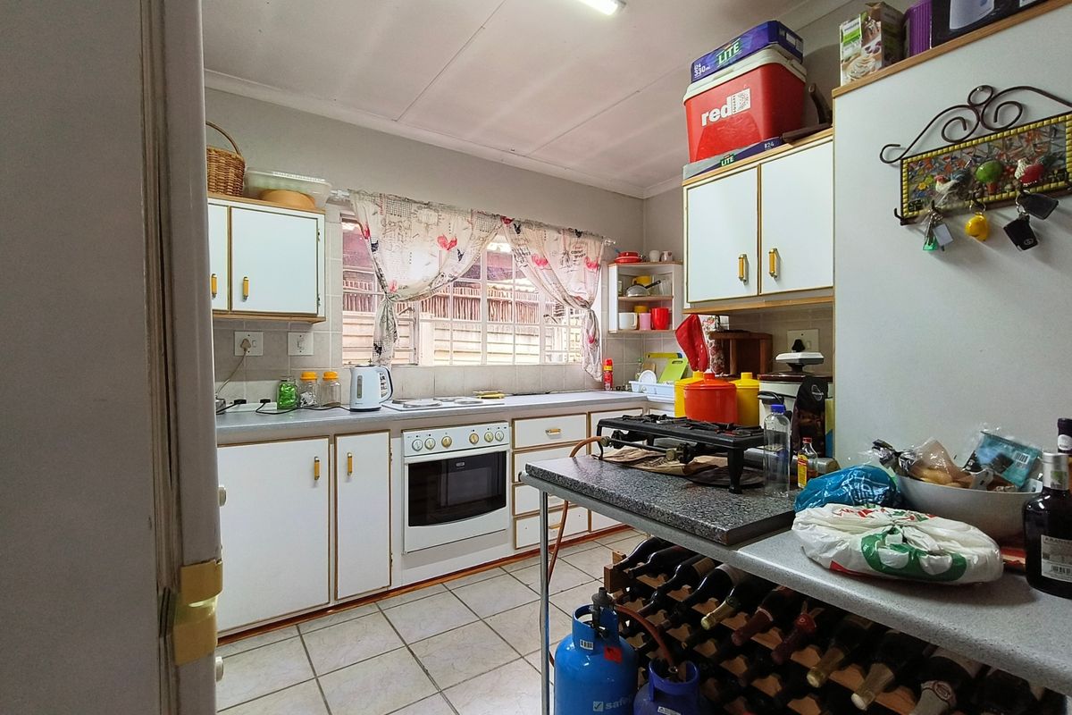 A functional kitchen featuring built-in cabinetry, tiled flooring, and a built-in oven, offering a practical layout with potential for modern updates.
