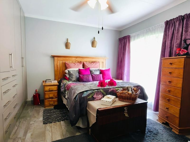 A well-maintained bedroom featuring built-in cupboards, tiled flooring, and a ceiling fan, offering a comfortable and functional living space.