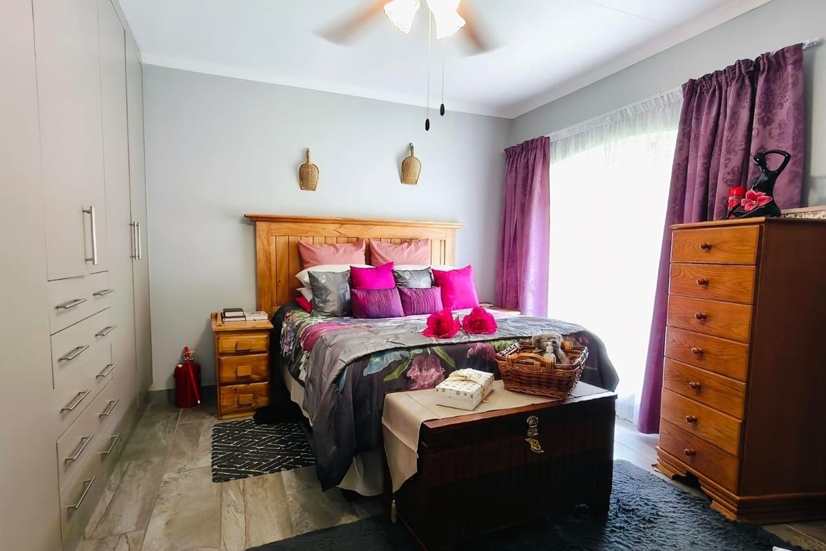 A well-maintained bedroom featuring built-in cupboards, tiled flooring, and a ceiling fan, offering a comfortable and functional living space.