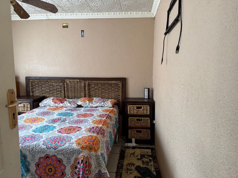 A bedroom featuring decorative ceiling tiles, a ceiling fan, and tiled flooring, currently requiring minor cosmetic updates to the wall finishes.