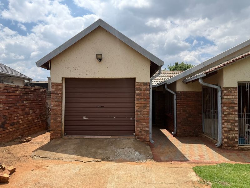 Front view of a single garage with a roller door, brick facade, and paved entrance path, showing signs of exterior wear.