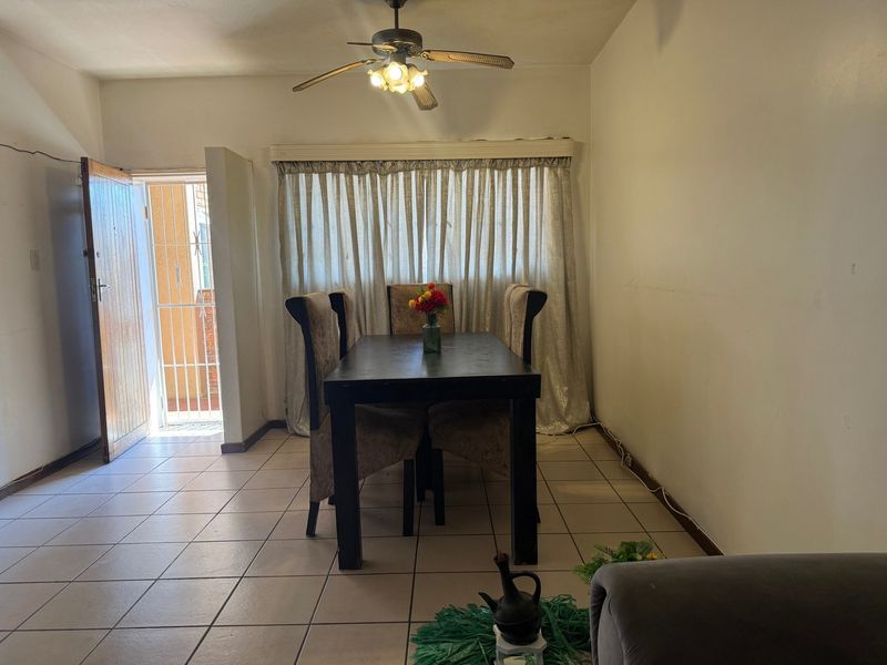 Dining area featuring tiled flooring, a ceiling fan, and direct access to an exterior entrance with a security gate.