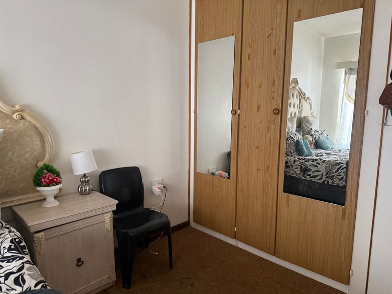A bedroom featuring built-in wooden wardrobes with integrated mirrors and carpeted flooring.