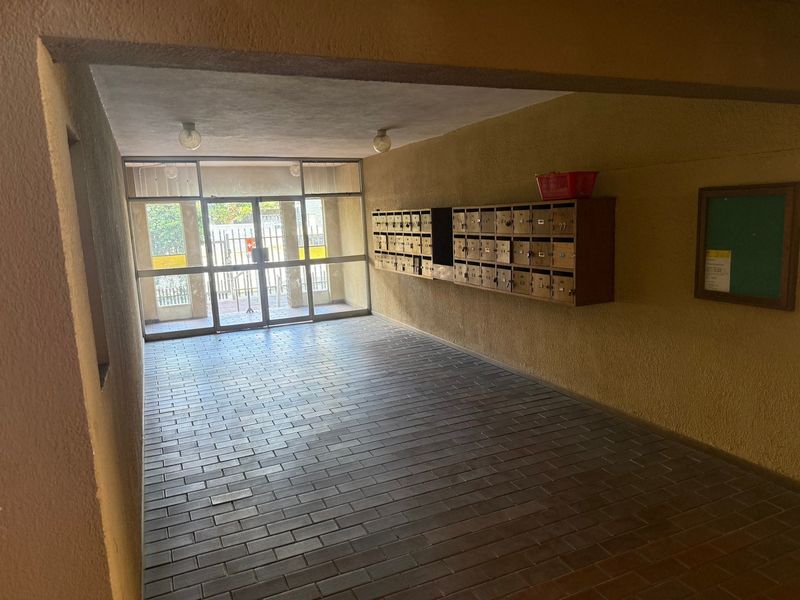 Apartment building entrance lobby featuring brick flooring, a glass entrance door, and a wall-mounted bank of mailboxes.