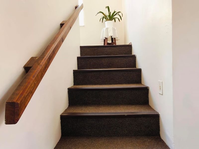 A carpeted staircase featuring a wooden handrail, providing access between levels within the townhouse.