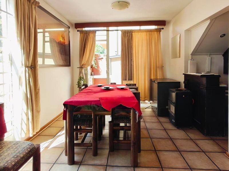 A dining area featuring tiled flooring, large windows, and a sliding glass door providing access to the exterior.