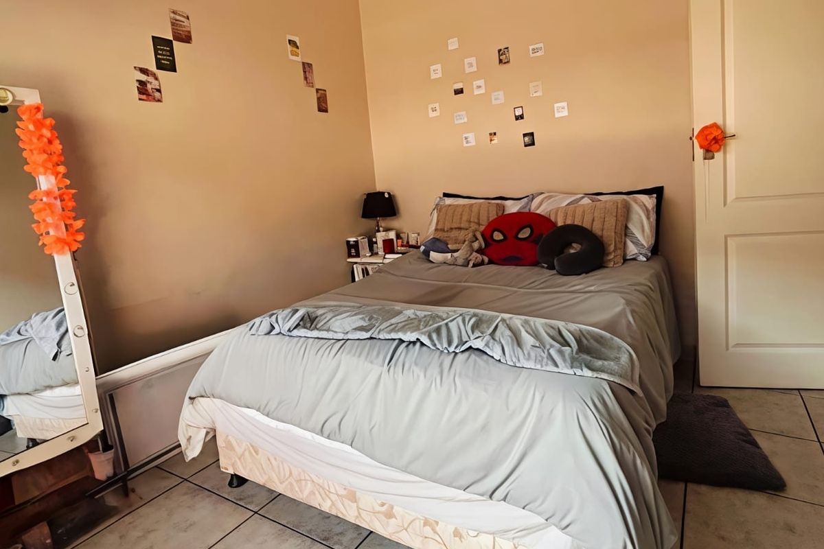 A standard bedroom featuring tiled flooring and a neutral wall finish, providing a functional space for rest.